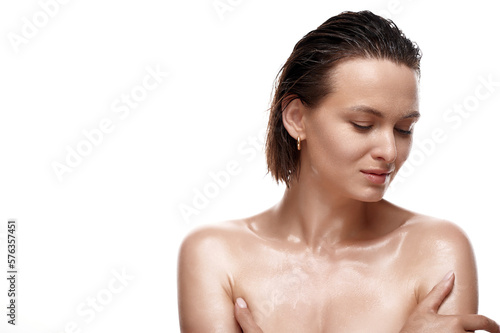 Sensual caucasian woman in the studio on white background with wet skin and wet hair hands and covers part of her body. Natural cosmetics  natural beauty.