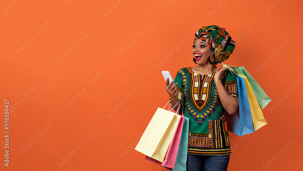 Fototapeta premium Emotional black woman in african costume shopping online, copy space