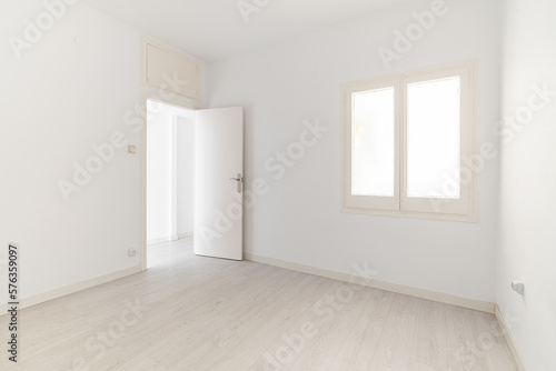 View of an empty white bright room with window without furniture after painting and renovation with wooden floor and baseboards. Concept of beautiful laconic interior for various inspiring ideas © Pavel