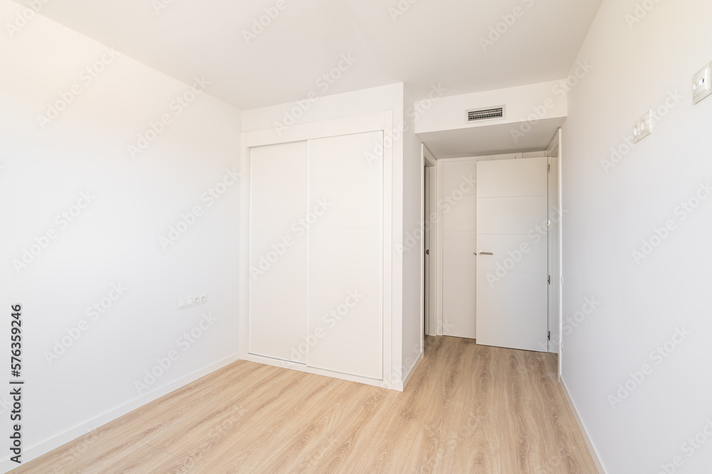 White empty sunny room with built-in wardrobe ventilation and two doors to the bathroom and exit. Concept of a new building or real estate for rent White empty sunny room with built-in wardrobe ventilation and two doors to the bathroom and exit. Concept of a new building or real estate for rent