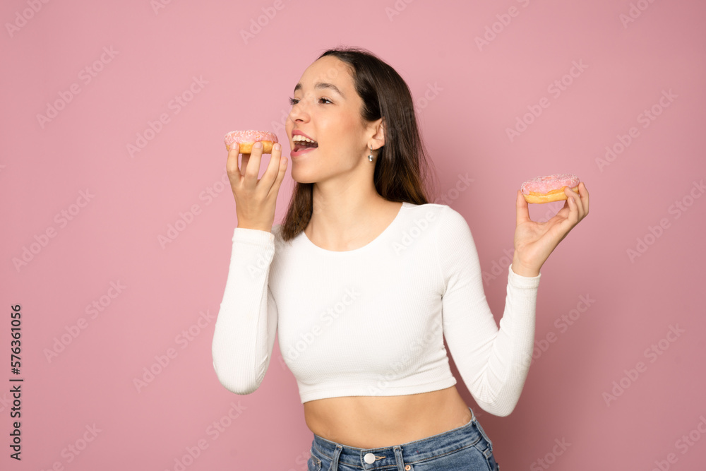 Portrait of a happy young woman holding donuts isolated over pink background Portrait of a happy young woman holding donuts isolated over pink background