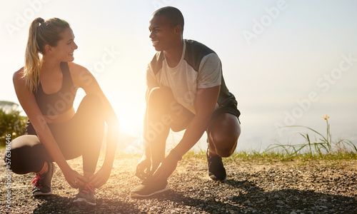 Grab your workout buddy and go. Shot of a fit young couple tying their shoelaces before a run outdoors. photo