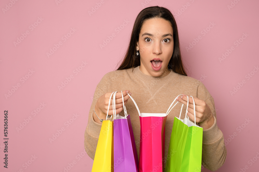 Close-up portrait of cheerful young girl looking into the shopping bags feeling excited isolated on pink background Close-up portrait of cheerful young girl looking into the shopping bags feeling excited isolated on pink background