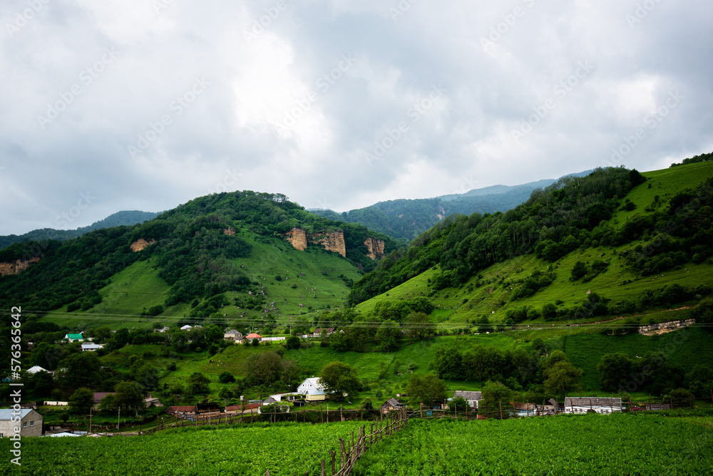 Summer landscapes of the Caucasus Mountains with bright green grass. Amazing mountain landscape on a rainy summer day. Rocky foothills of the Caucasus.
