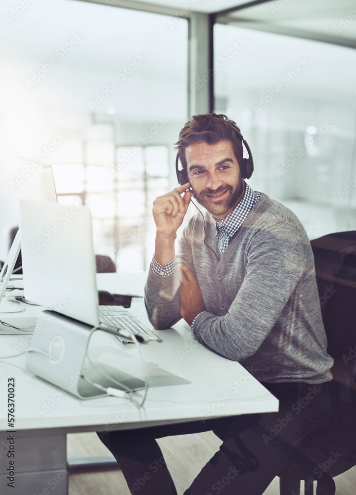 Service with a smile. High angle shot of a handsome young businessman wearing a headset while sitting at his desk. Service with a smile. High angle shot of a handsome young businessman wearing a headset while sitting at his desk.