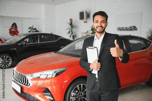 Successful indian businessman in a car dealership - sale of vehicles to customers. © Serhii