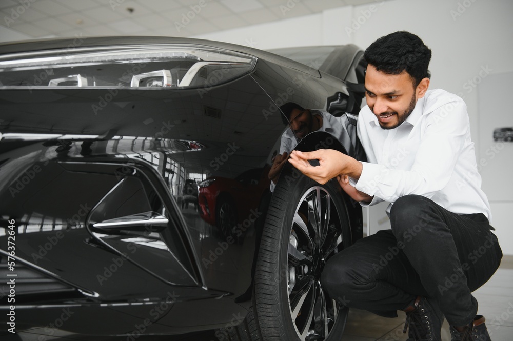 Fototapeta premium A young Indian man chooses a new car at a car dealership
