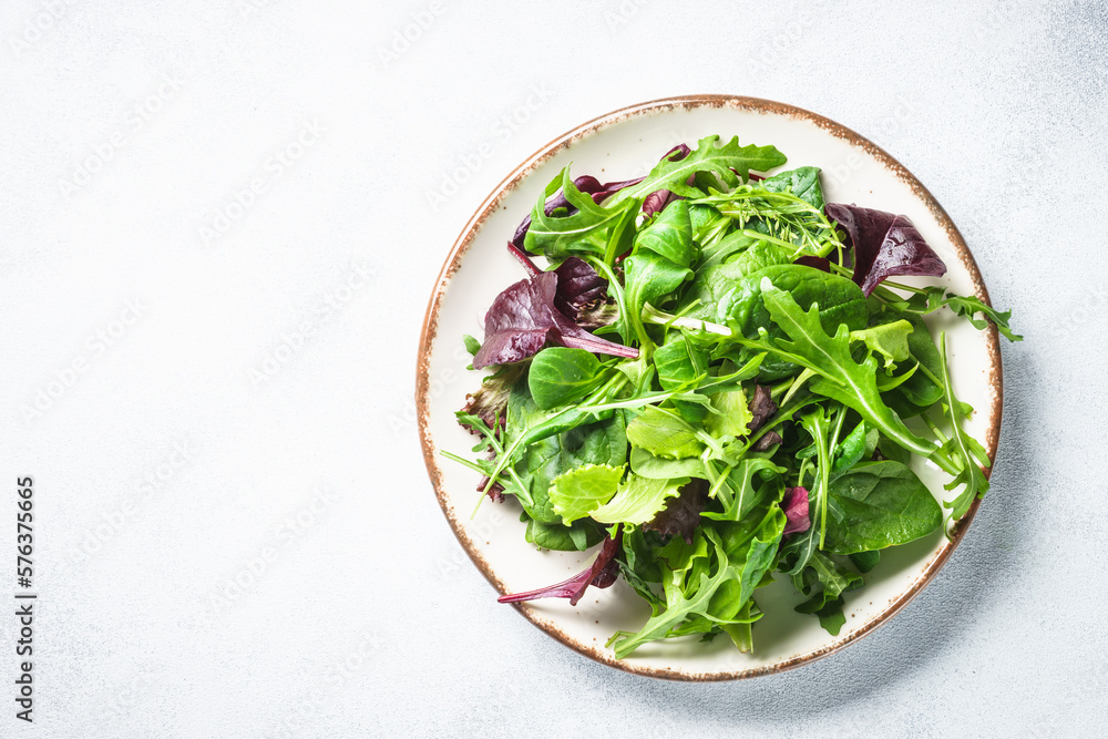 Green salad, fresh leaves in white plate. Top view. Green salad, fresh leaves in white plate. Top view.