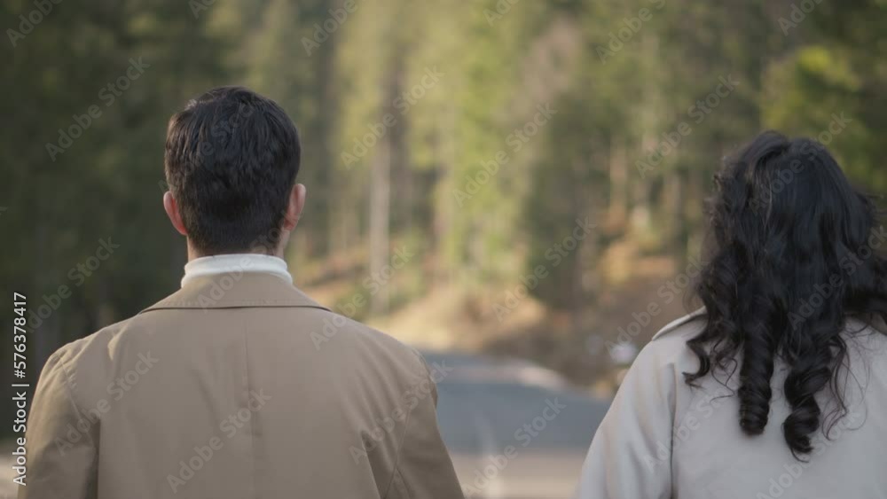 Romantic couple walking along highway in mountains forest. Man takes woman hand and romantic date outdoors. Joyful people boy and girl sit, walk on road. Love couple having fun while walking in nature Romantic couple walking along highway in mountains forest. Man takes woman hand and romantic date outdoors. Joyful people boy and girl sit, walk on road. Love couple having fun while walking in nature