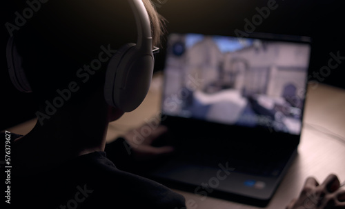 Canvastavla Young gamer is wearing a headset playing FPS video games at home