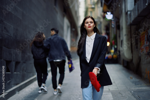 Fashion woman tourist in stylish clothes in a jacket and red beret walking down a narrow city street flying hair and happy travel, French style, cinematic color, retro style.