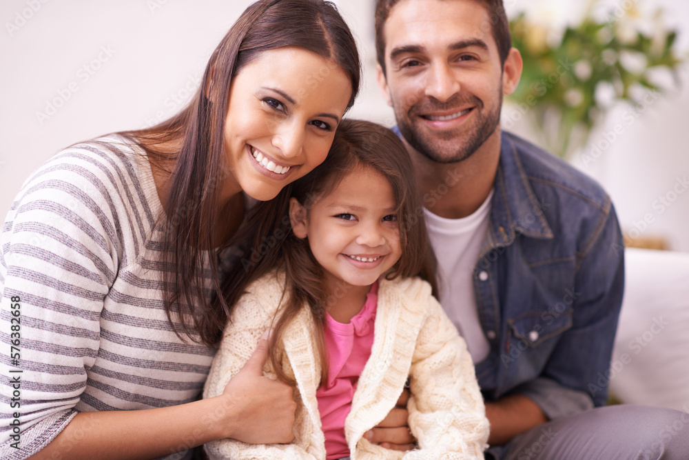 Theres an abundance of love in this home. Portrait of a happy young family sitting together at home. Theres an abundance of love in this home. Portrait of a happy young family sitting together at home.