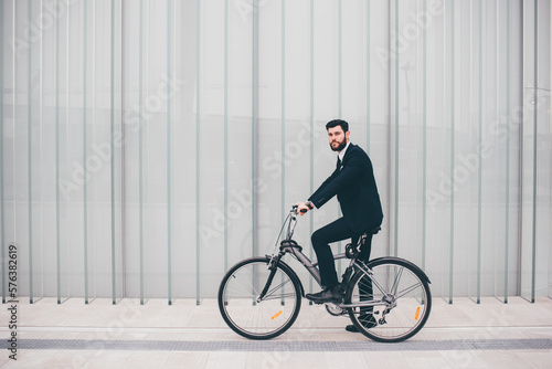 Contemporary bearded young stylish businessman going to work by bike