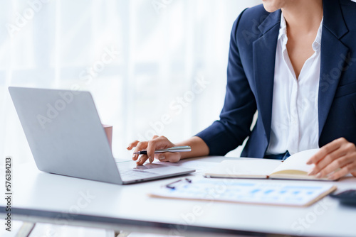 Businesswoman working using laptop computer to record and type data.