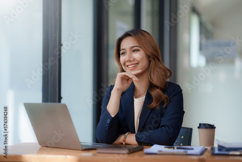 Attractive asian businesswoman sitting working on laptop thinking new idea at office.