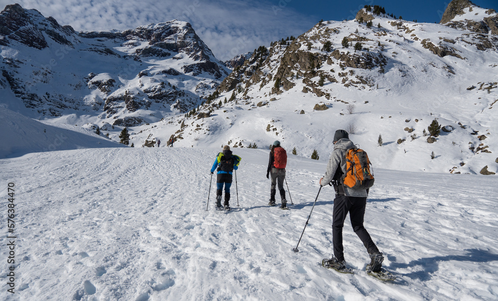 group of mountaineers doing a route with snowshoes in winter on a sunny day in the pyrenees