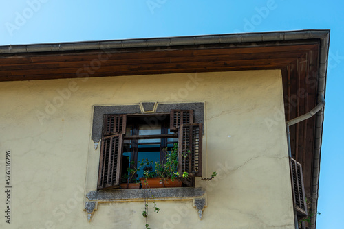 Old wooden window with wooden shutters, stone frame and flower pots on an old cracked yellow wall in Antakya before the earthquake of 2023. 