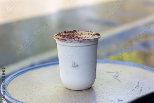 plastic cup of  Cavendish Banana fresh milk Whey shake  sprinkle with cocoa powder focus view 