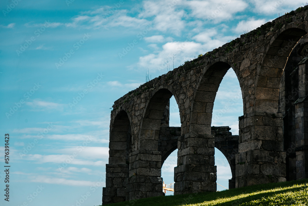 Historic Santa Clara Aqueduct in Vila do Conde, Portugal. View from the curved point near the monastery castle, blue sky with clouds.