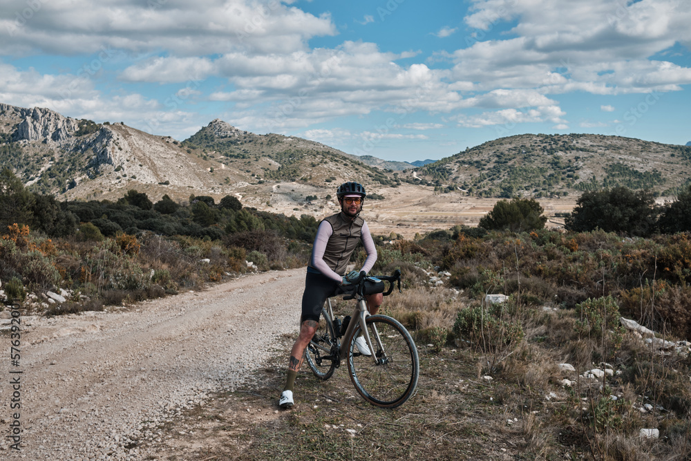 Gravel cycling: portrait of a man and his trusty bike.Cyclist is enjoying the serene mountain scenery on his gravel bike.Castell de Castells, Alicante, Spain