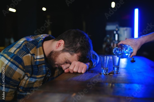 It was a hard day. Depressed young man drinking vodka in bar photo