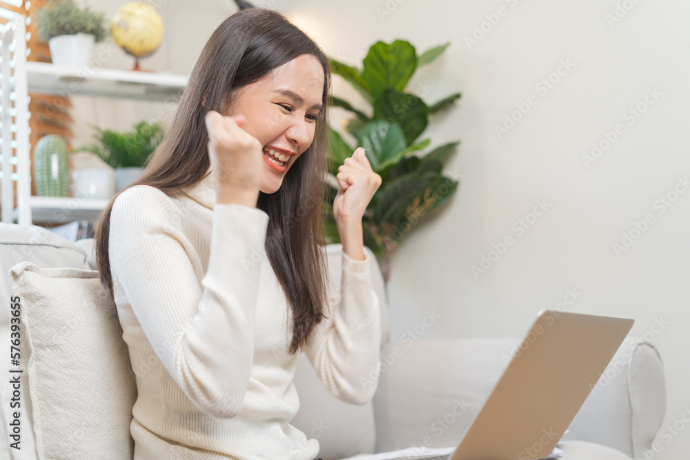 Happy cheerful, satisfied asian young freelancer woman, girl sitting on sofa or couch, using laptop computer in living room at home, looking and smiling at screen, entrepreneur enjoying with work, wfh Happy cheerful, satisfied asian young freelancer woman, girl sitting on sofa or couch, using laptop computer in living room at home, looking and smiling at screen, entrepreneur enjoying with work, wfh