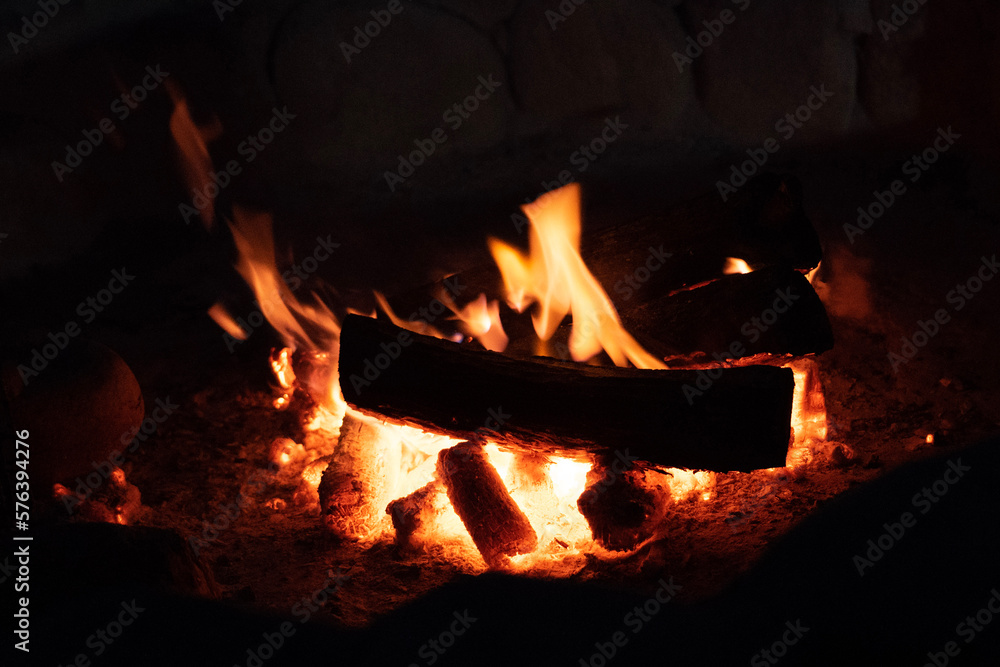 Wooden log burning in a campfire at night