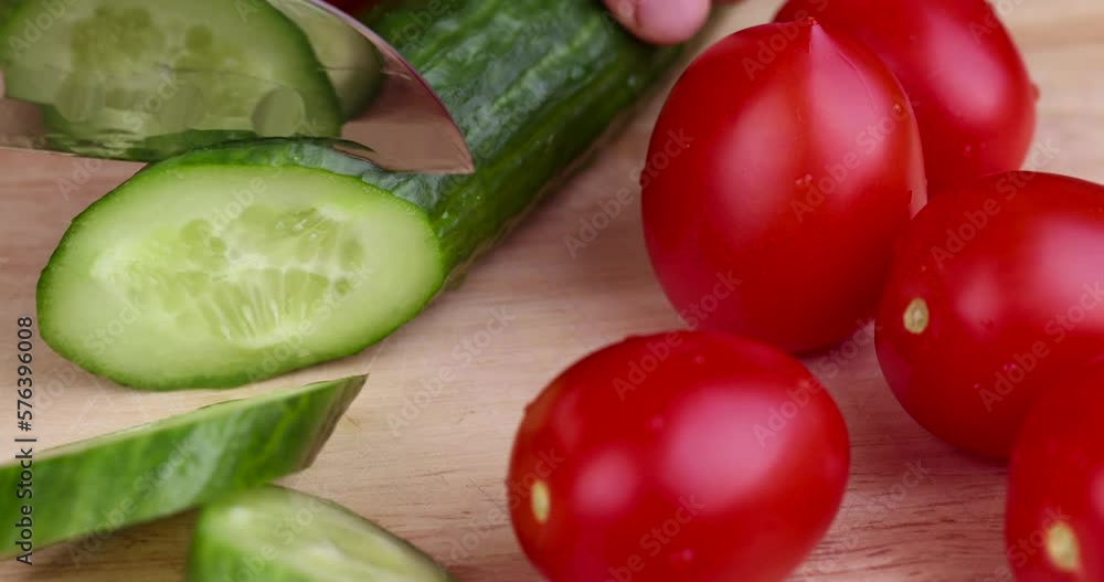 Slice a green ripe cucumber in thin circles, washed a long green cucumber during slicing for salad Slice a green ripe cucumber in thin circles, washed a long green cucumber during slicing for salad