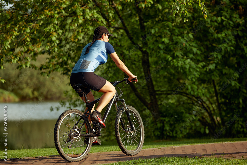 Happy brunette girl in sportswear riding a bike in the park. Happy brunette girl in sportswear riding a bike in the park.