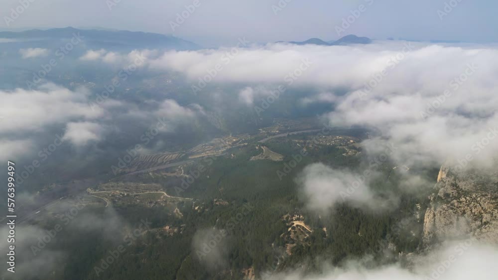 Drone video flying above the clouds.Panoramic view of a mountain valley with a village lying in a lowland. Calp, Alicante, Spain Drone video flying above the clouds.Panoramic view of a mountain valley with a village lying in a lowland. Calp, Alicante, Spain