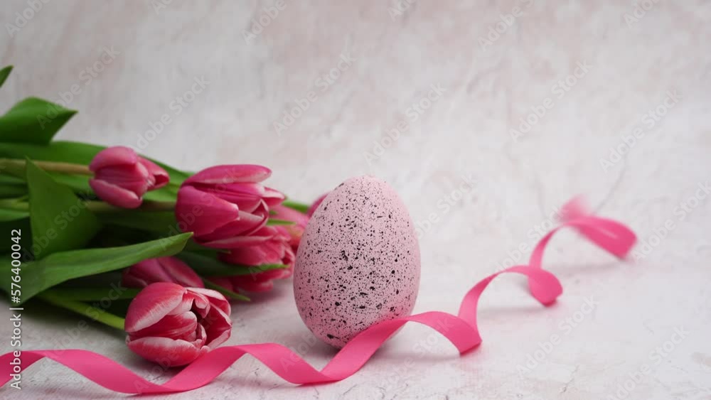 Easter egg with ribbon and pink tulips on light concrete background Easter egg with ribbon and pink tulips on light concrete background