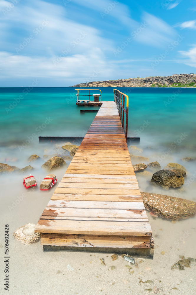 A wooden jetty reaching into the sea on a tropical, Caribbean island. A long shutter time has been used to give the sea an ethereal look. 