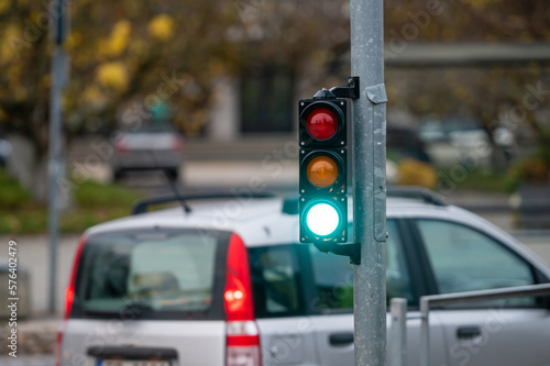 view of city traffic with traffic lights, in the foreground a semaphore with a green light, closeup