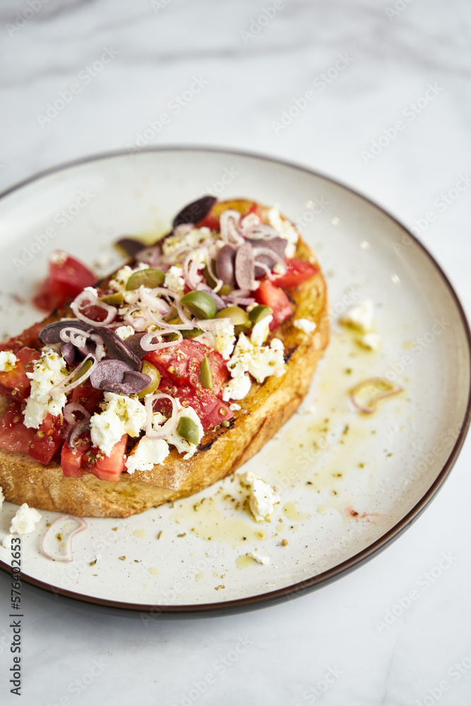 Dakos salad traditional Greek salad with soaked and crunchy barley rusks or bread, topped with juicy tomatoes, feta cheese, onions, olives, and a drizzle of olive oil. Popular apetizer