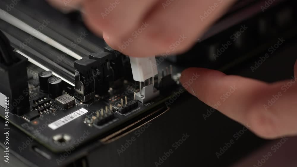 Extreme close-up of unrecognizable man plugging power cable connector from motherboard to SSD drive illumination and to CPU cooler, slow motion. Stages of upgrading or assembling desktop computer. Extreme close-up of unrecognizable man plugging power cable connector from motherboard to SSD drive illumination and to CPU cooler, slow motion. Stages of upgrading or assembling desktop computer.