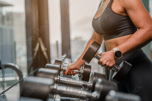 Asian Women in sportswear working out with weights over exercise bench exercising are lifting dumbbells at fitness gym in the morning.Fitness muscular body.Fitness, gym, workout and healthy concepts.