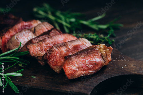 Grilled beef chuck roll steaks on wooden background with rosemary and thyme