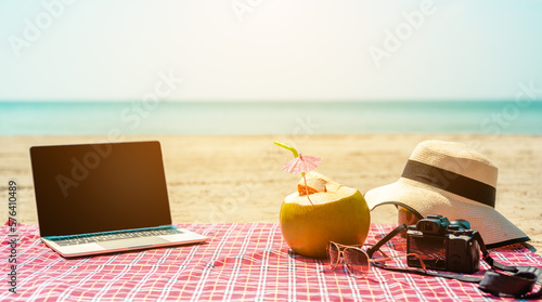 Fototapeta Naklejka Na Ścianę i Meble -  Women beach hat and sunglasses, laptop ,camera, coconuts,work and travel,tropical sandy beach, summer travel, vacation and summer holiday concepts.