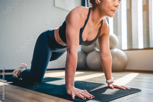 Asian woman doing plank and stretch legs and arms on yoga mat at Gym in the morning.Exercise  Workout and fitness lifestyle concepts.