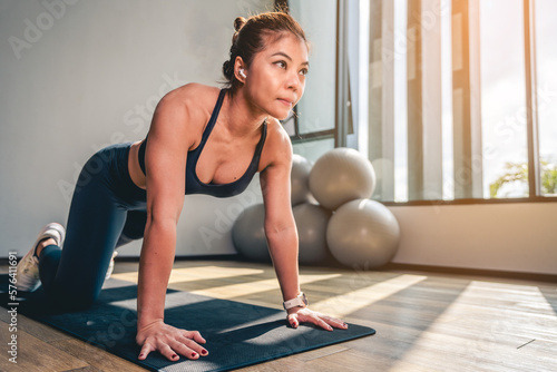 Asian woman doing plank and stretch legs and arms on yoga mat at Gym in the morning.Exercise, Workout and fitness lifestyle concepts.