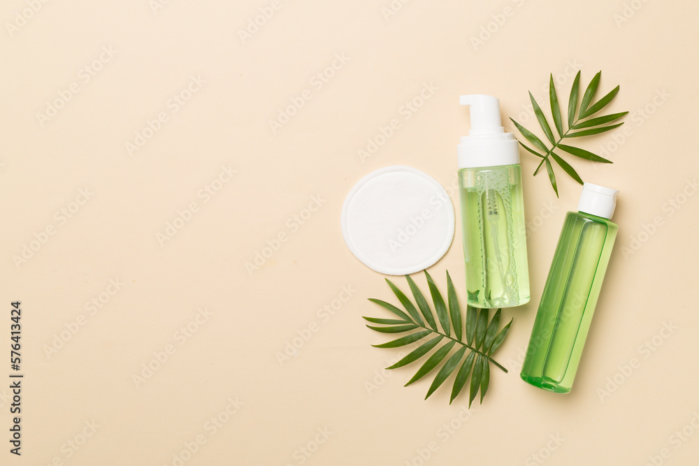 Foaming facial cleanser and micellar water with eco pads on color background, top view Foaming facial cleanser and micellar water with eco pads on color background, top view