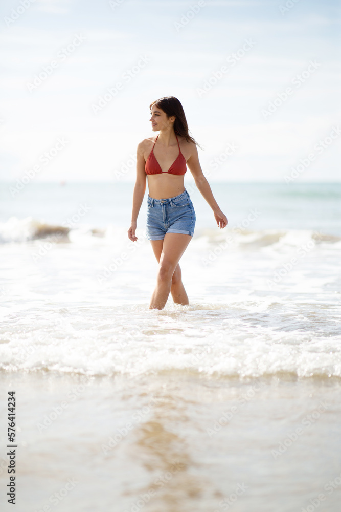 Beautiful young woman walking in water on the beach Beautiful young woman walking in water on the beach