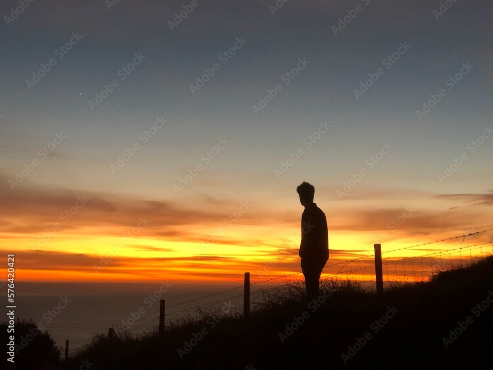 Silhouette of man against vivid orange sunset