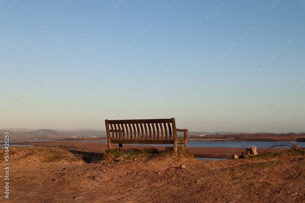 Empty bench on beach with coastline landscape background