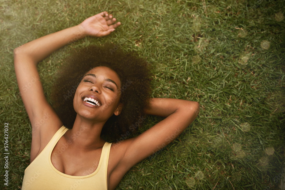 This is the life. Shot of a young woman laughing while relaxing on the grass. - obrazy, fototapety, plakaty 