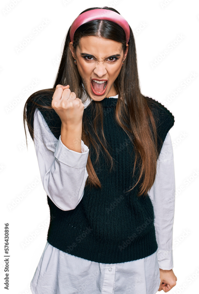 Young beautiful woman wearing casual white shirt angry and mad raising fist frustrated and furious while shouting with anger. rage and aggressive concept. Young beautiful woman wearing casual white shirt angry and mad raising fist frustrated and furious while shouting with anger. rage and aggressive concept.