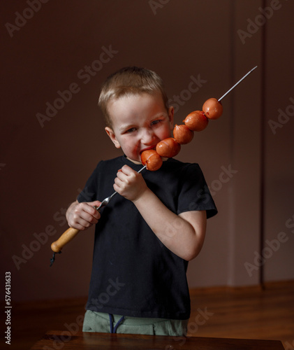 boy eats sausages on a skewer