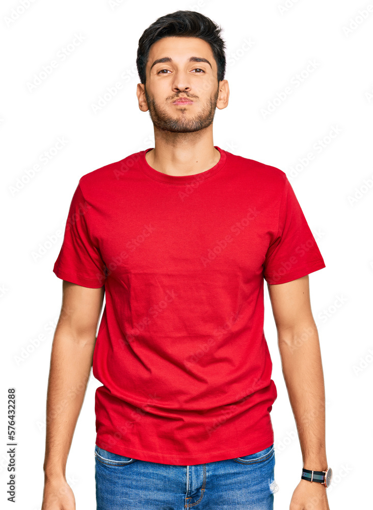 Young handsome man wearing casual red tshirt puffing cheeks with funny face. mouth inflated with air, crazy expression. Young handsome man wearing casual red tshirt puffing cheeks with funny face. mouth inflated with air, crazy expression.