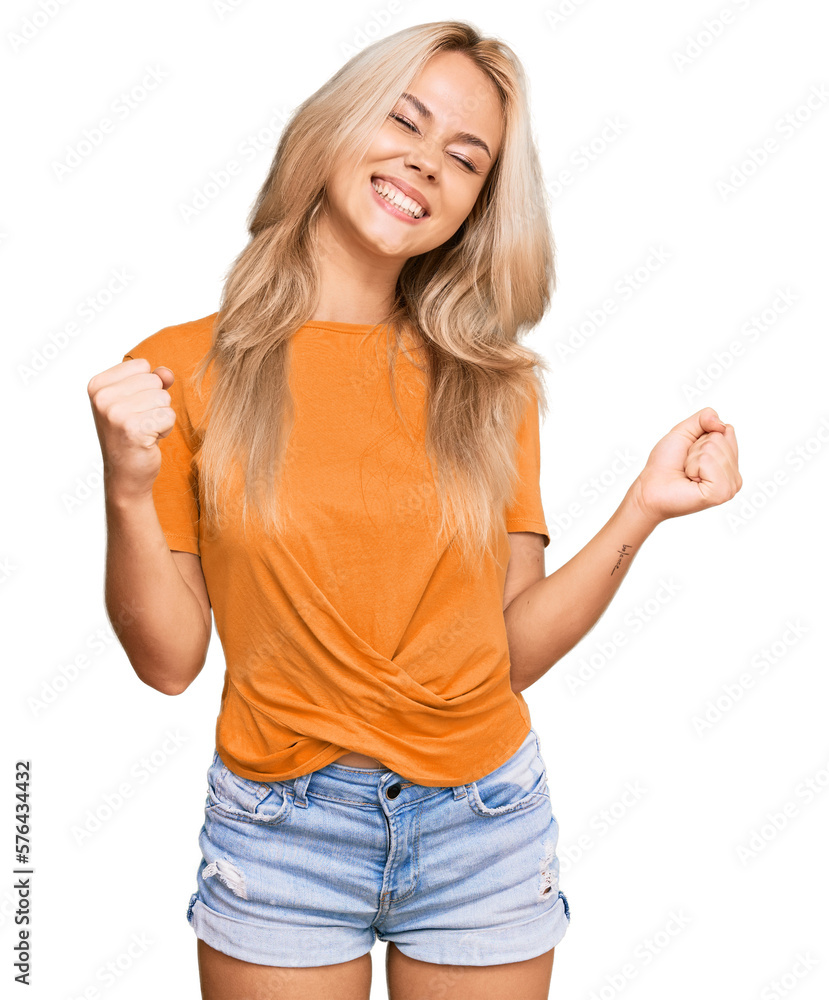 Young blonde girl wearing casual clothes very happy and excited doing winner gesture with arms raised, smiling and screaming for success. celebration concept. Young blonde girl wearing casual clothes very happy and excited doing winner gesture with arms raised, smiling and screaming for success. celebration concept.