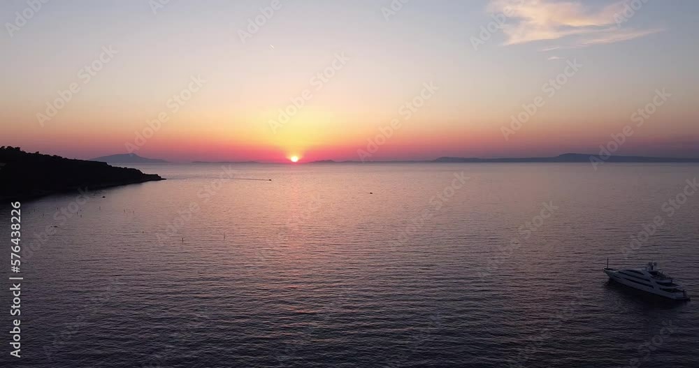 Colorful sunset above the sea surface with sail boat, sun goes down, blue and orange clouds flow in sky. Small yacht boat sailing in calm open sea at sunset. Floating on Sea Surface Golden Sky Colorful sunset above the sea surface with sail boat, sun goes down, blue and orange clouds flow in sky. Small yacht boat sailing in calm open sea at sunset. Floating on Sea Surface Golden Sky